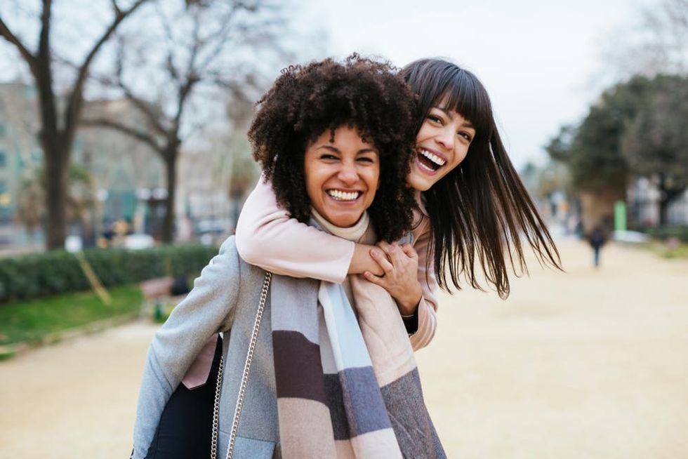 Friends laugh together as they walk through a park