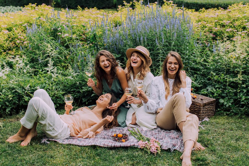 friends laughing and drinking wine at a picnic