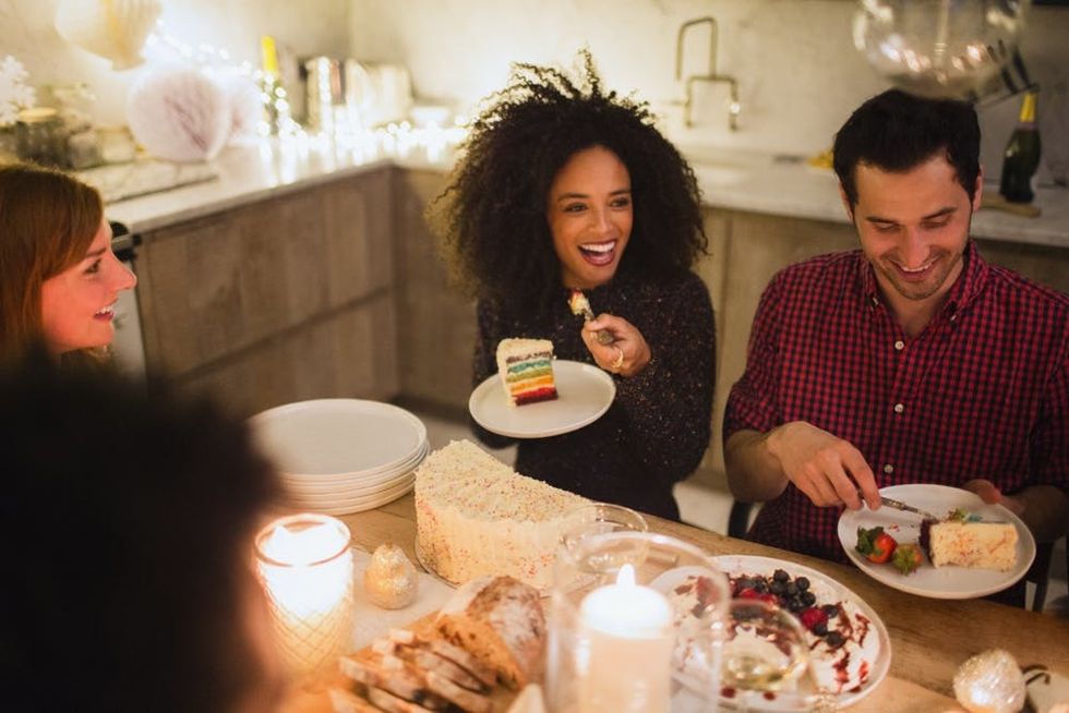 Friends serve up slices of cake at a candlelit table
