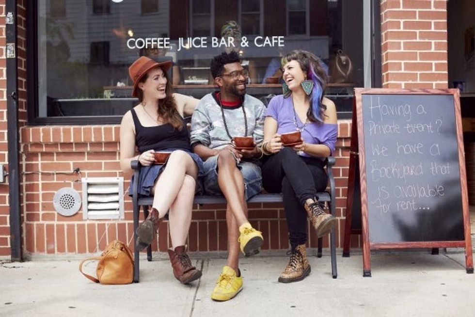 Friends sitting outside coffee shop on city street