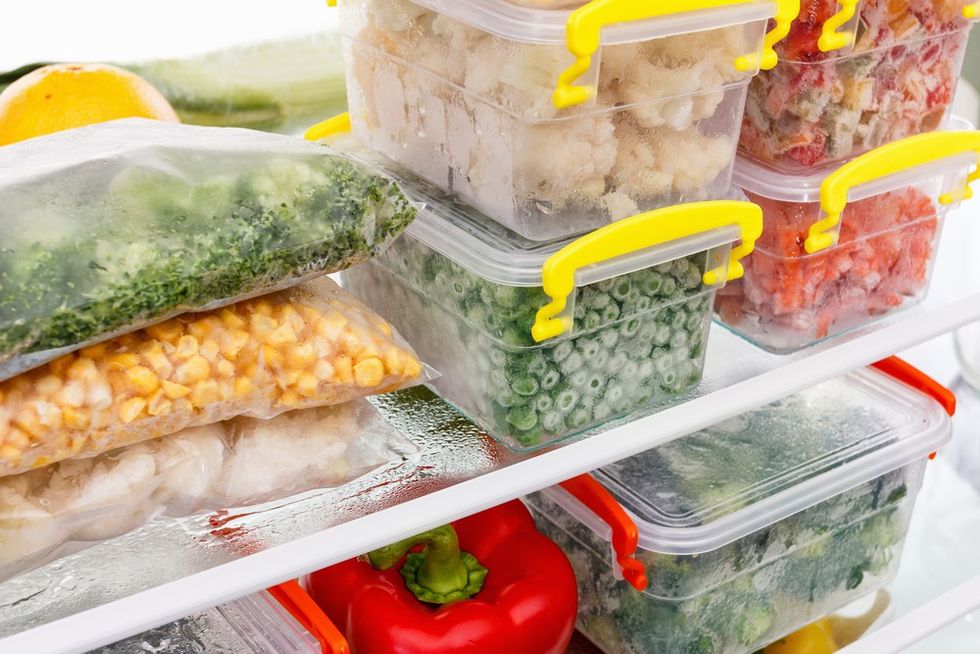 Frozen vegetables in bags and containers, organized on a refrigerator shelf.
