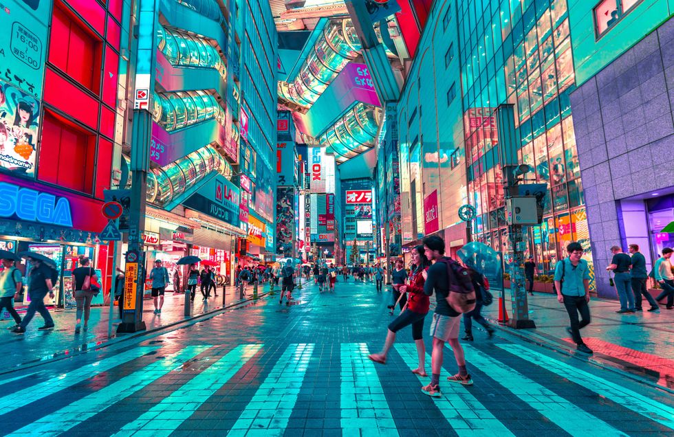 Futuristic street scene with neon lights and people walking in a vibrant cityscape.