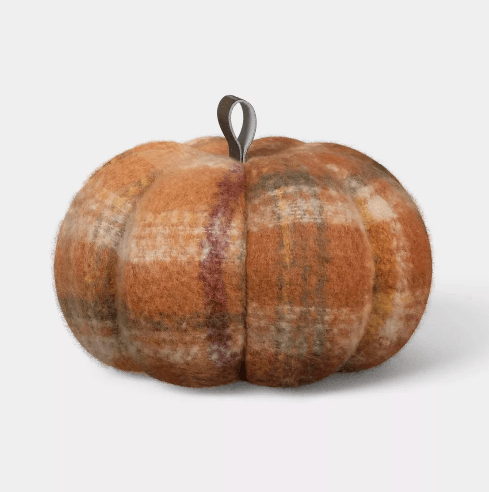 Fuzzy plaid pumpkin decoration with a brown stem on a light background.