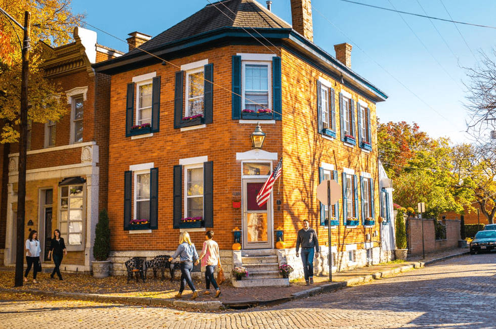 German Village, Columbus OH Brick house on a sunny, tree-lined street corner with people walking by in autumn.