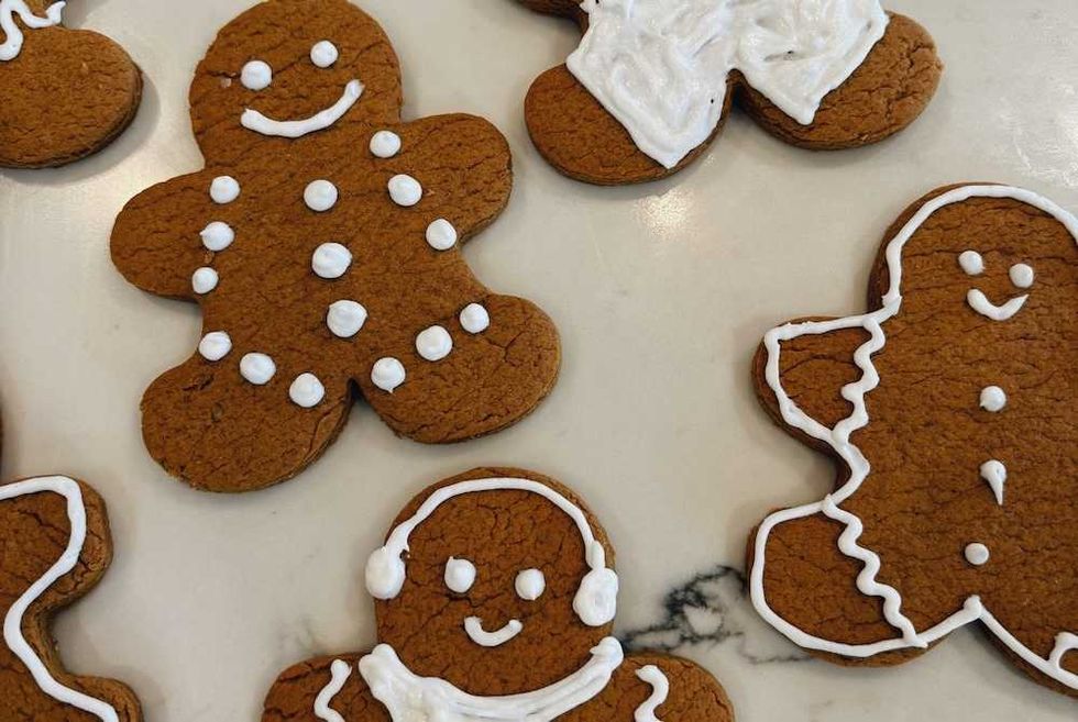 Gingerbread cookies decorated with white icing on a marble surface.
