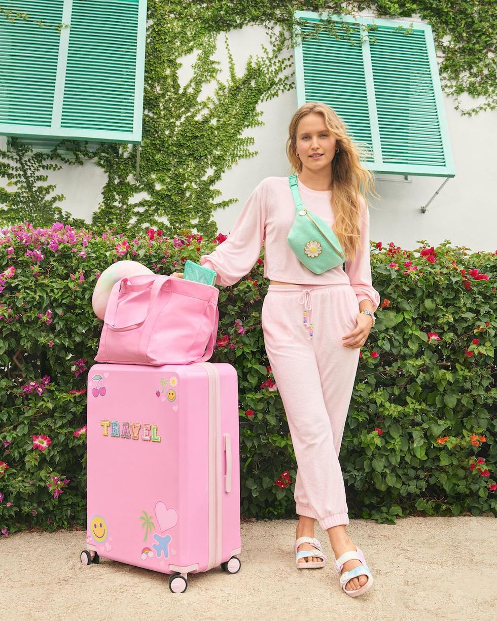 girl in pink sweat suit with pink suitcase and bags