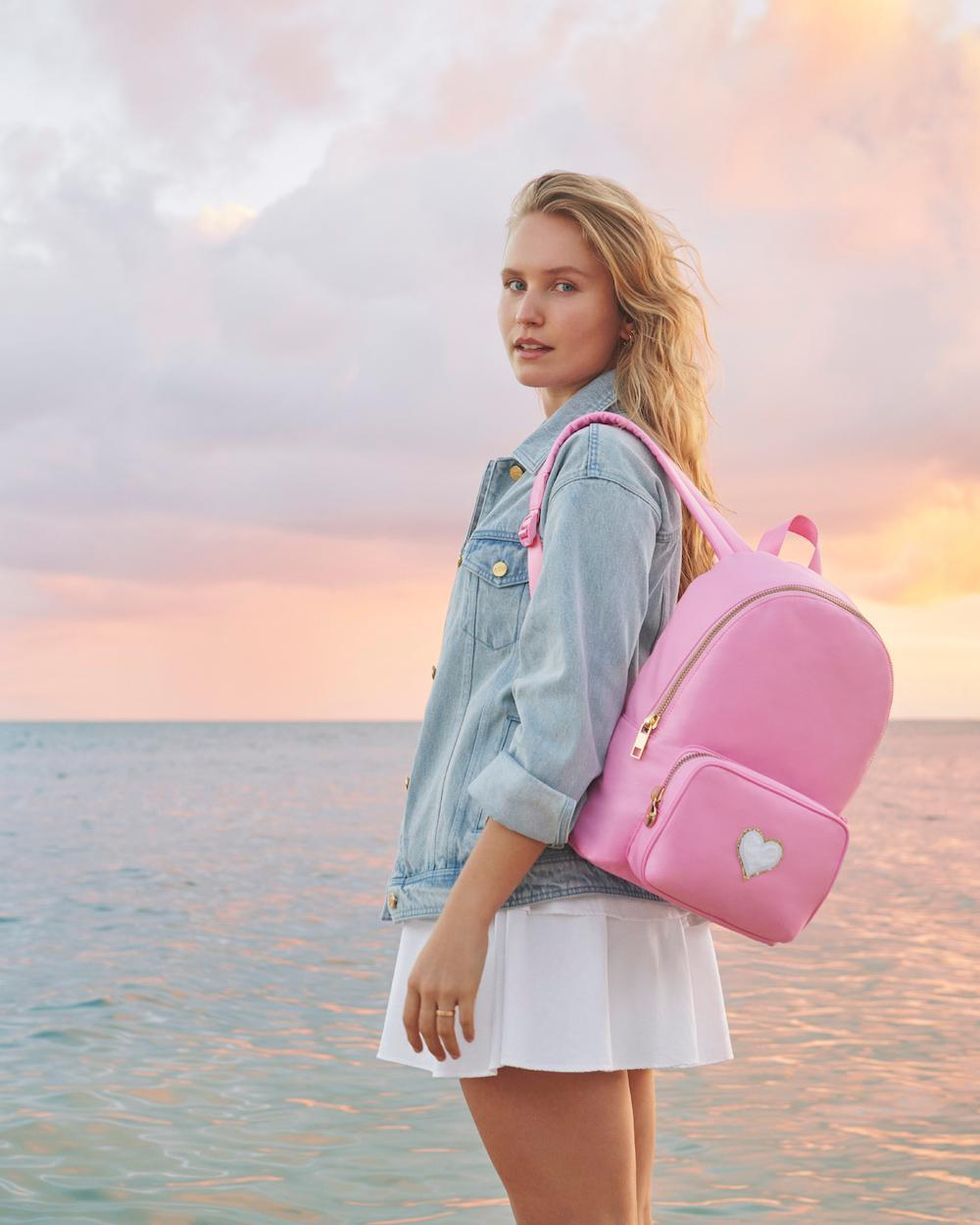 girl in white dress and denim jacket with a pink backpack