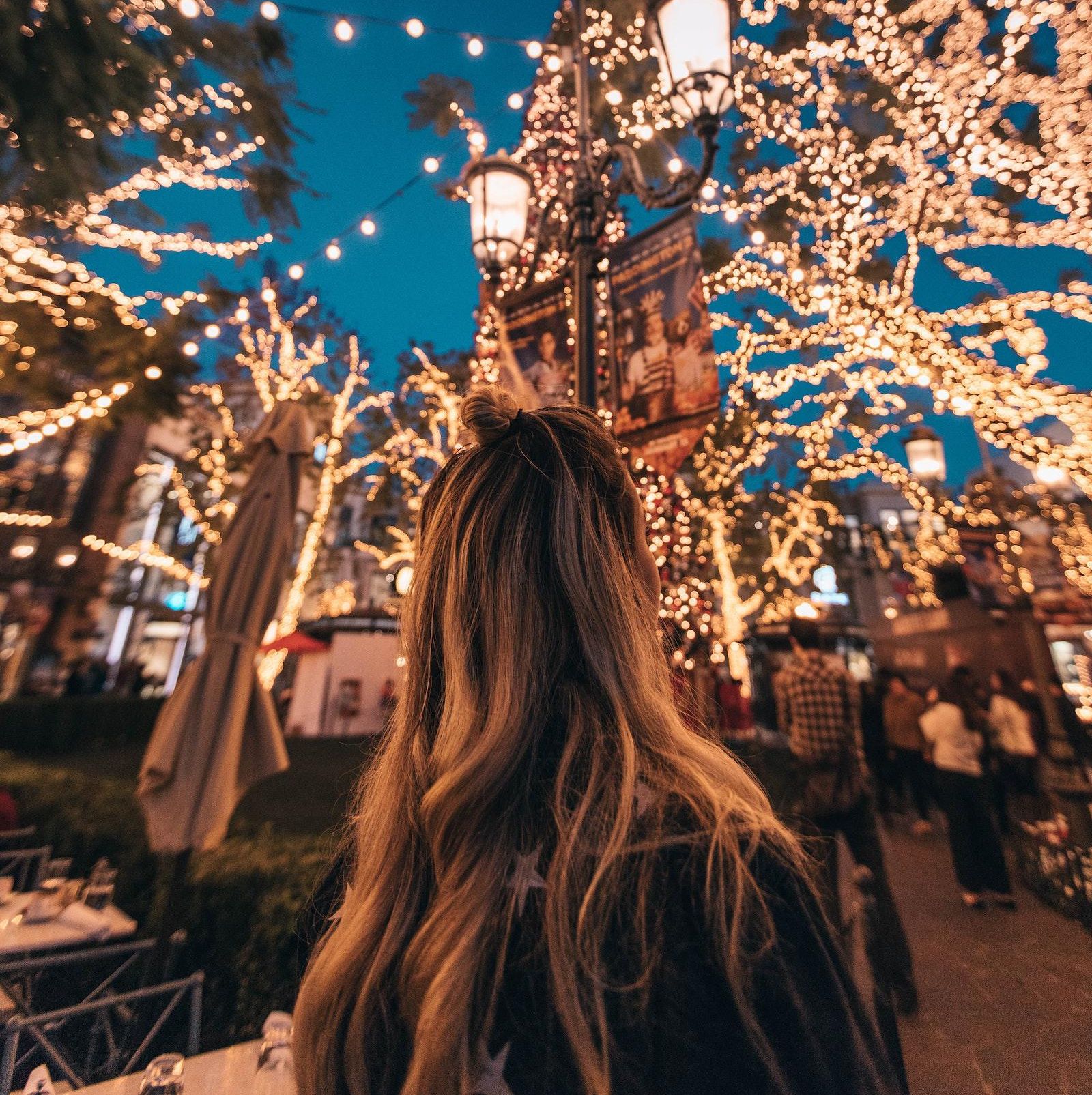 girl standing under the Christmas lights during Christmas travel