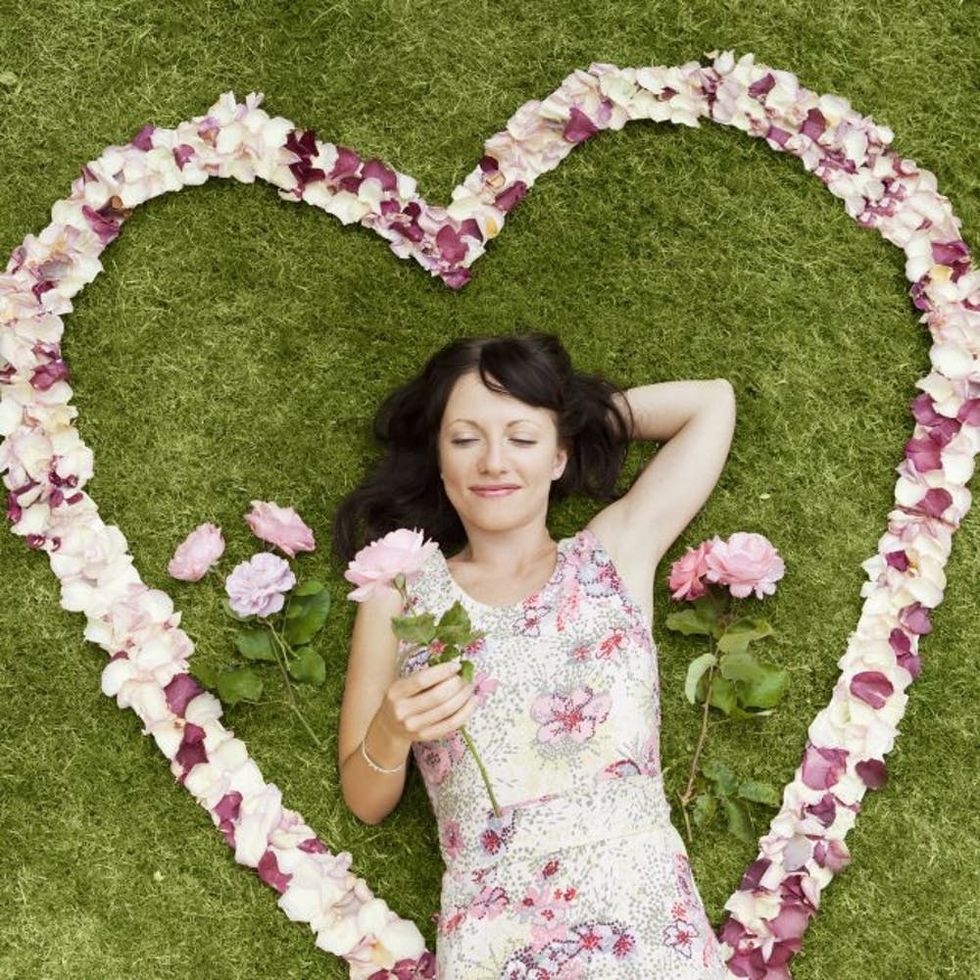 Girl surrounded with rosepedals heart.