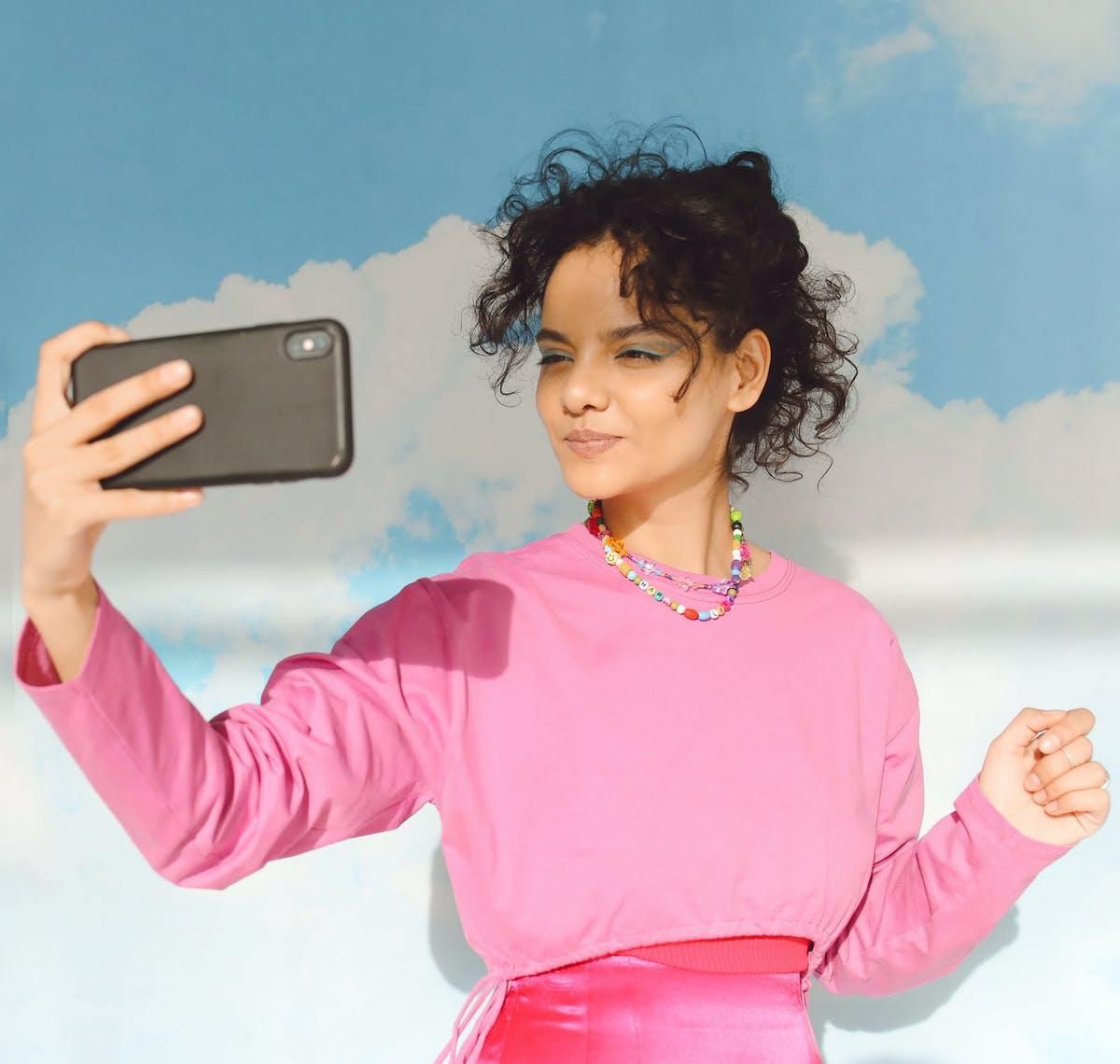 girl taking selfie against a cloud wall bereal app