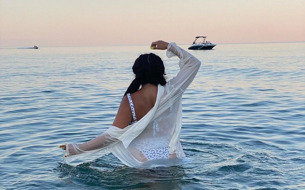 girl wading in the ocean at sunset