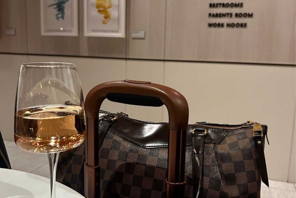Glass of wine and checkered bag on table in modern setting.