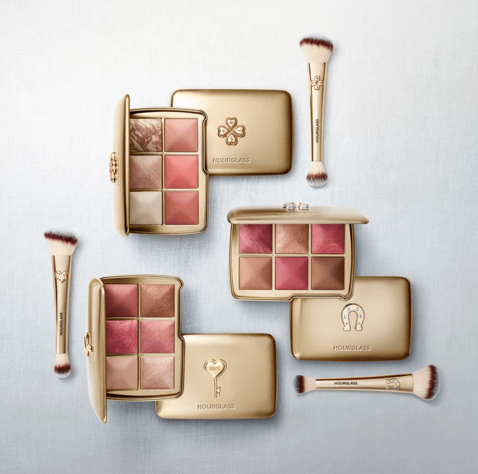 Gold cosmetic palettes and brushes with blush shades on a light background.
