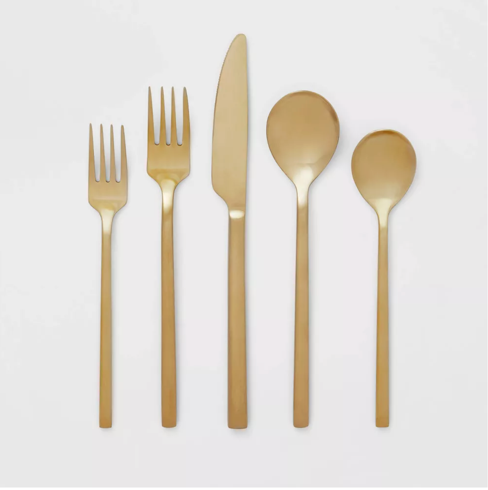 Gold cutlery set on white background; two forks, knife, spoon, and teaspoon.