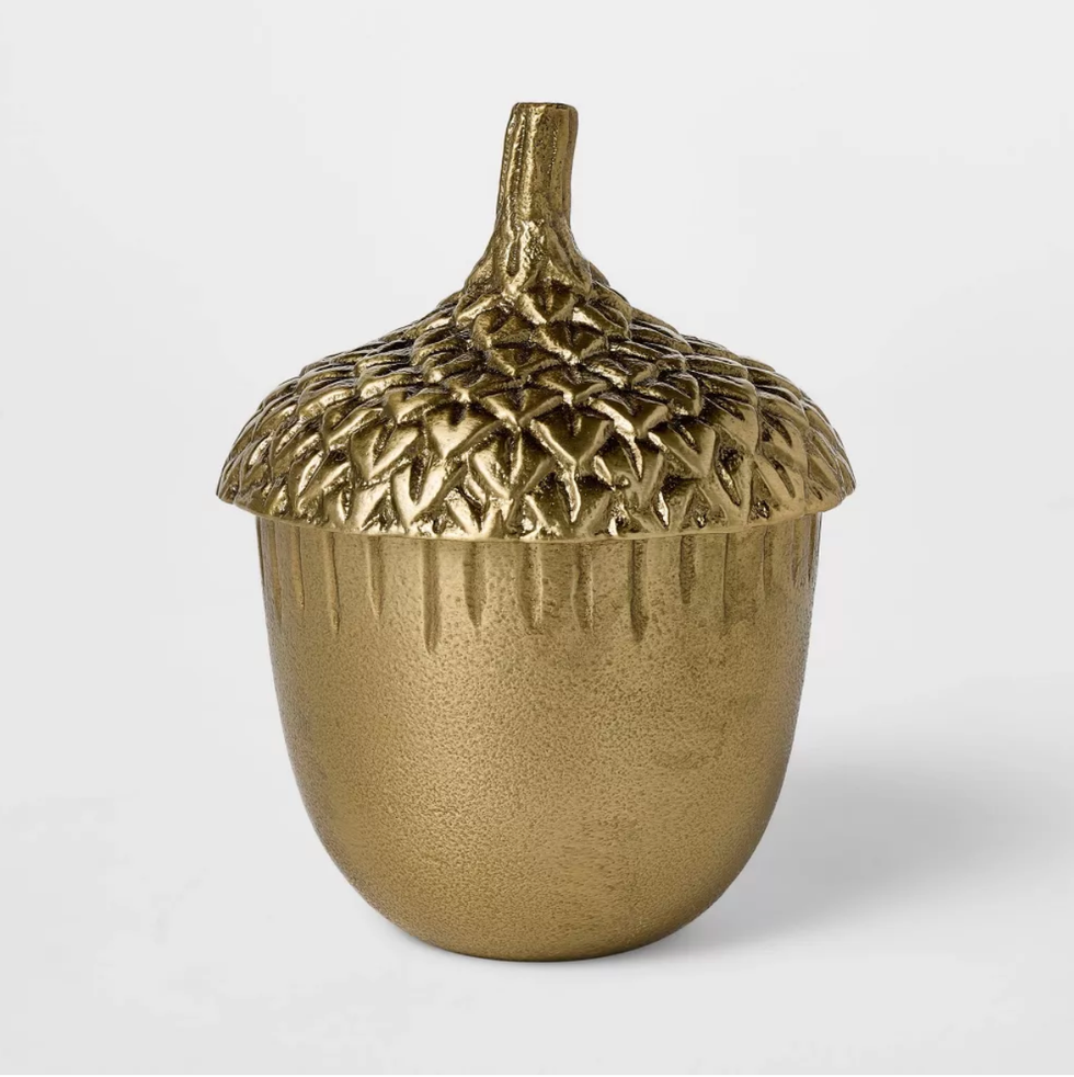 Gold decorative acorn with textured cap and smooth body against a plain background.