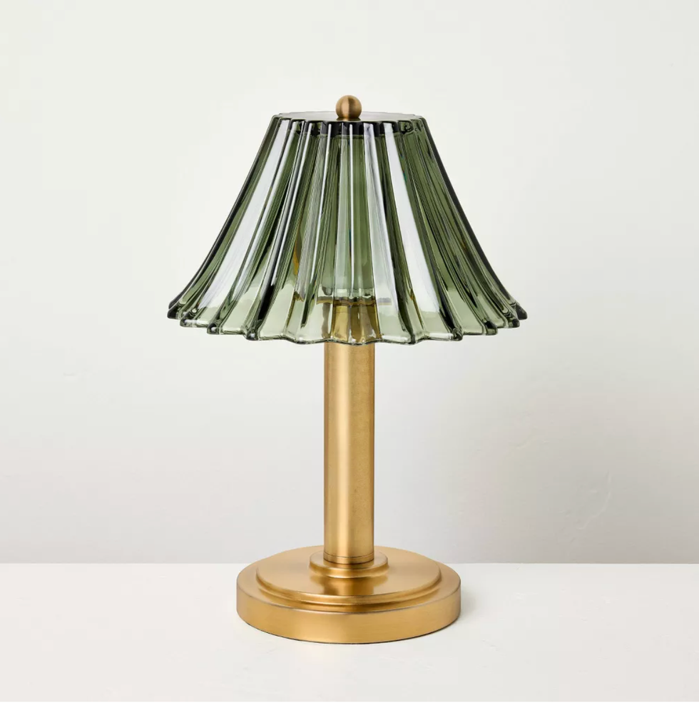 Gold lamp with ribbed green glass shade on a white surface.