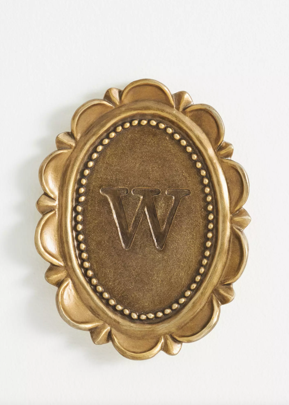 Gold ornate oval plaque with letter "W" embossed in the center.