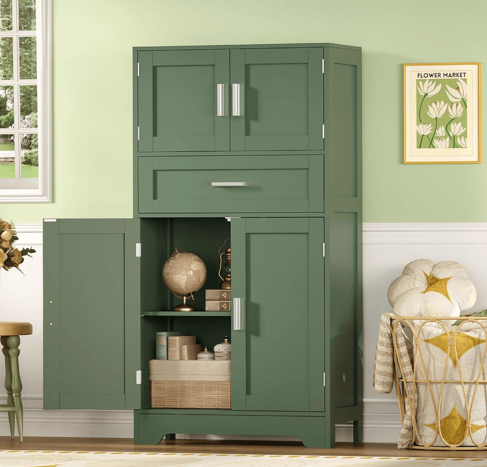 Green cabinet with open lower doors, globe, and decor; flower print and window in background.