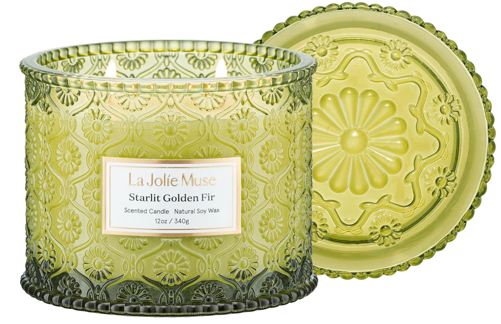 Green embossed glass candle jar labeled "Starlit Golden Fir" with matching decorative lid.