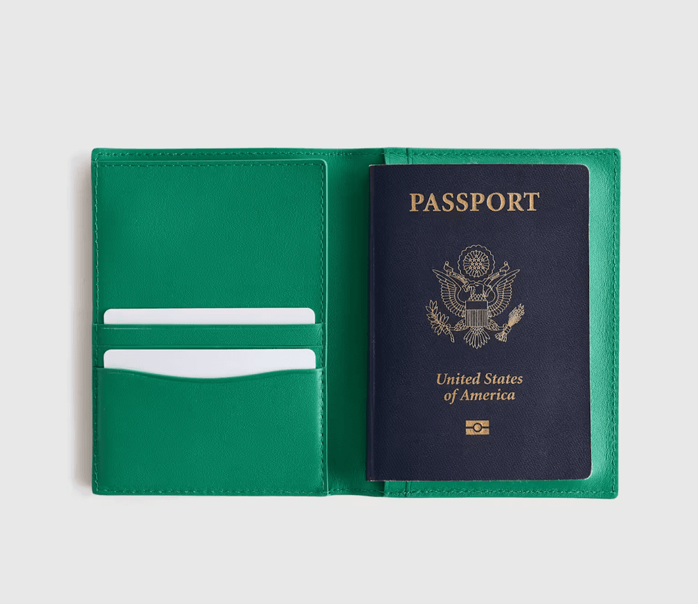 Green passport holder with a blue U.S. passport and white cards inside.