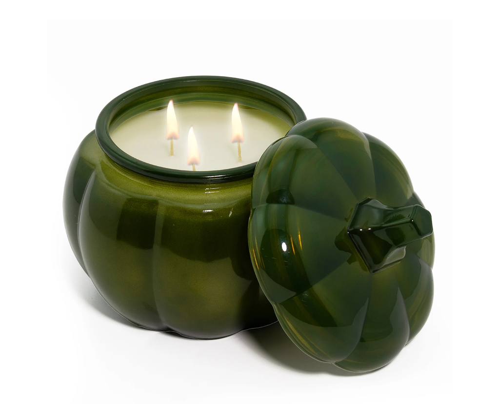 Green pumpkin-shaped candle holder with three lit wicks and a matching lid.