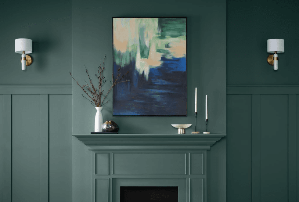 Green room with abstract art, modern sconces, and minimalist decor on a mantel.
