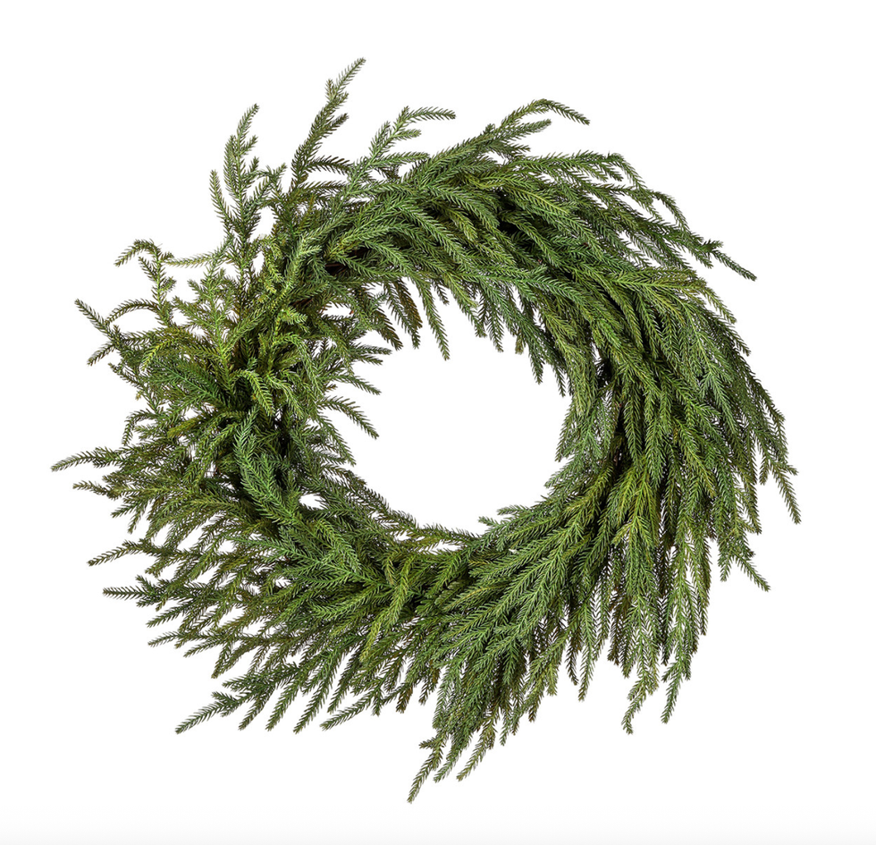 Green wreath made of pine branches on a white background.