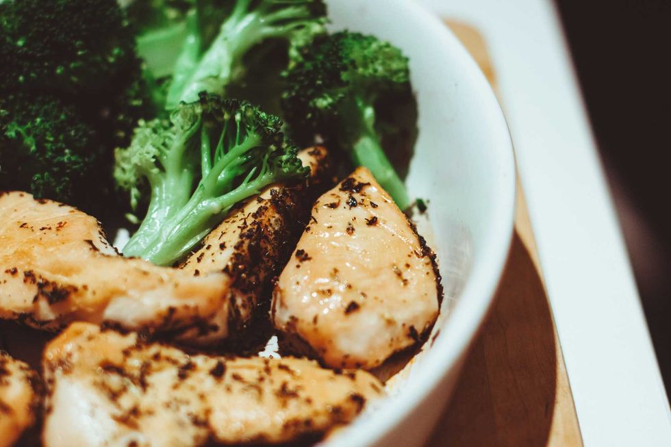 Grilled chicken and broccoli in a white bowl.