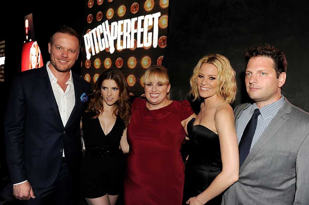 Group of five people at "Pitch Perfect" event, smiling in front of the movie logo.