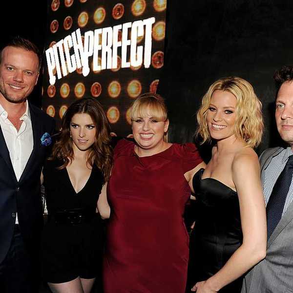 Group of five people at "Pitch Perfect" event, smiling in front of the movie logo.