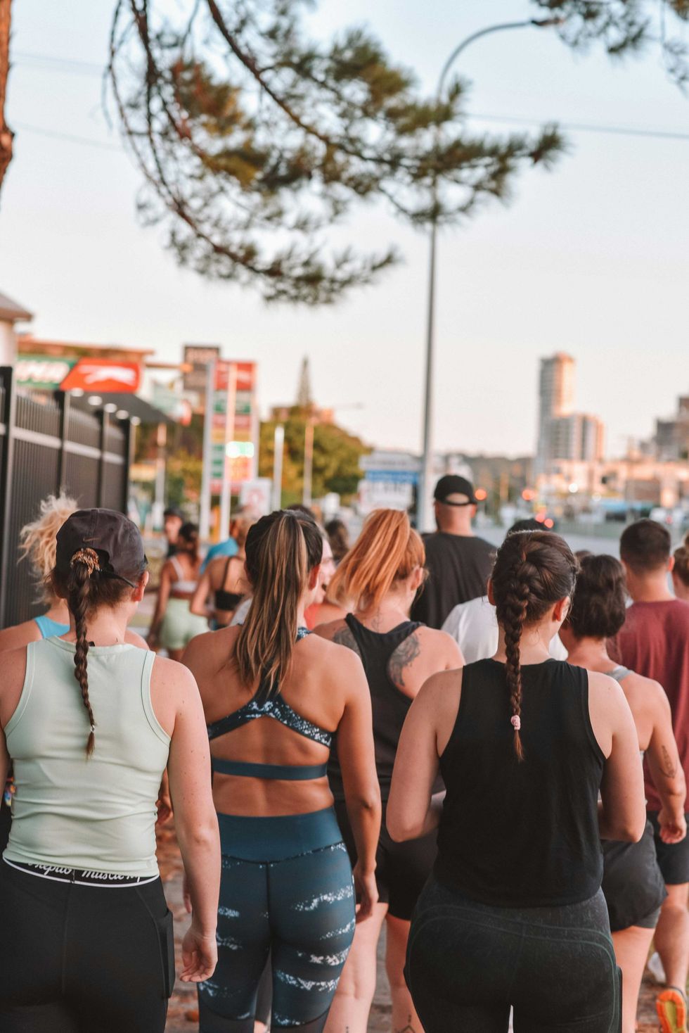 Group of people walking outdoors in athletic wear on a tree-lined street.
