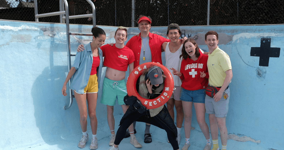 Group posing in an empty pool with a lifebuoy labeled "SEA SECTION."