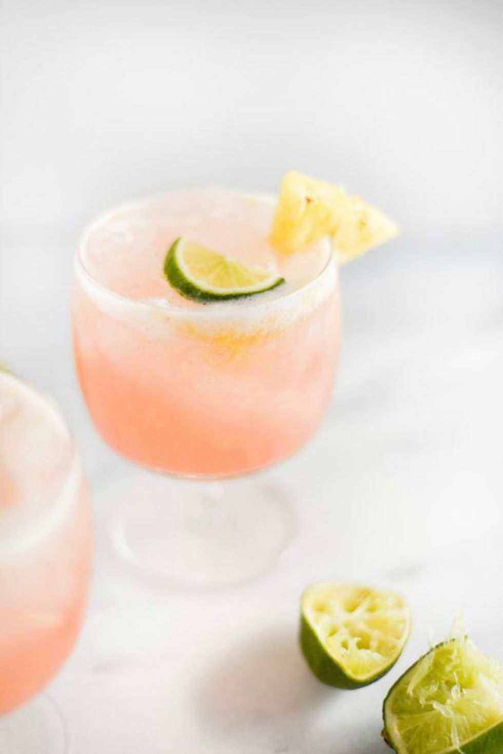 Guava Pineapple & Coconut Cocktail in a clear glass with pineapple and lime garnish