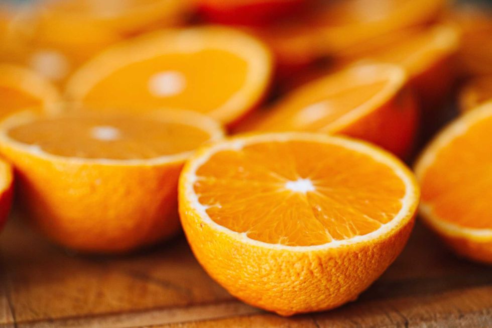 Halved oranges on a wooden surface, showcasing vibrant orange flesh.