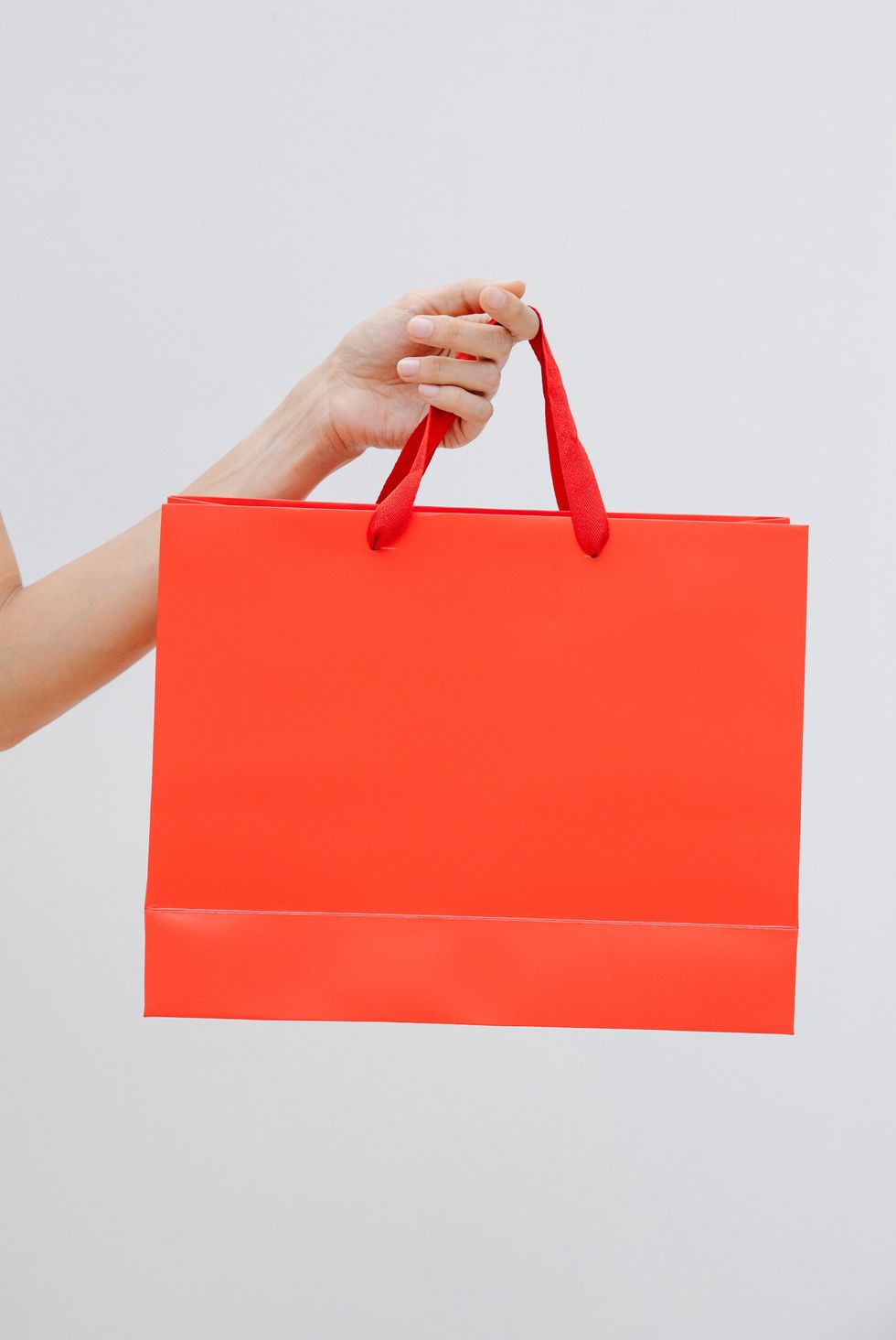 hand holding a red shopping bag
