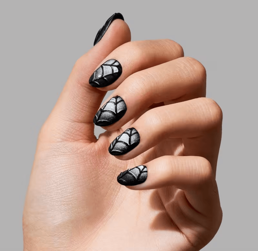 Hand with black nails featuring white spiderweb designs.