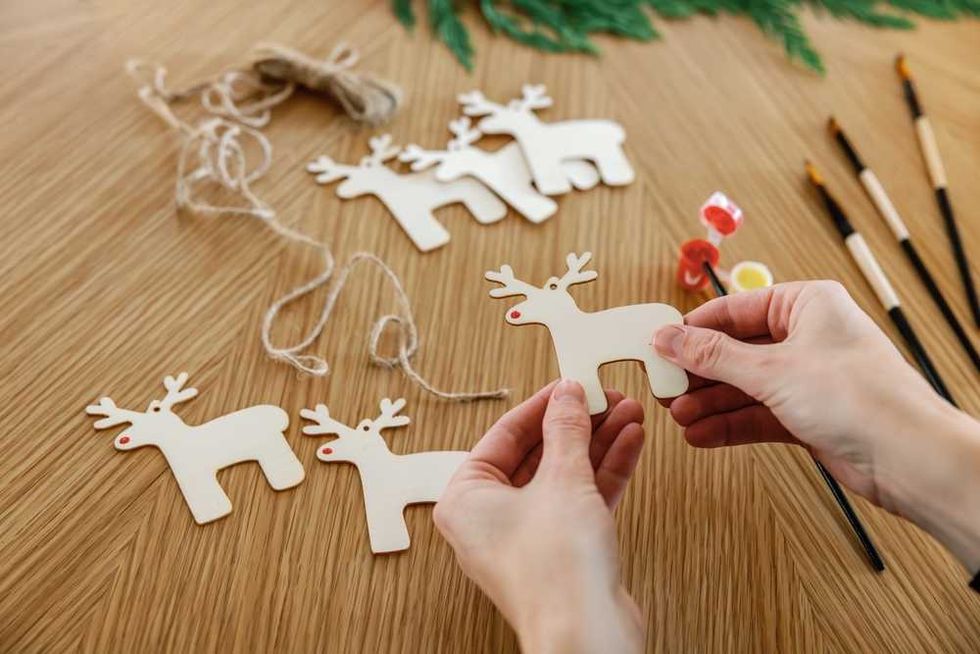 Hands holding a cutout reindeer for a Christmas craft project.