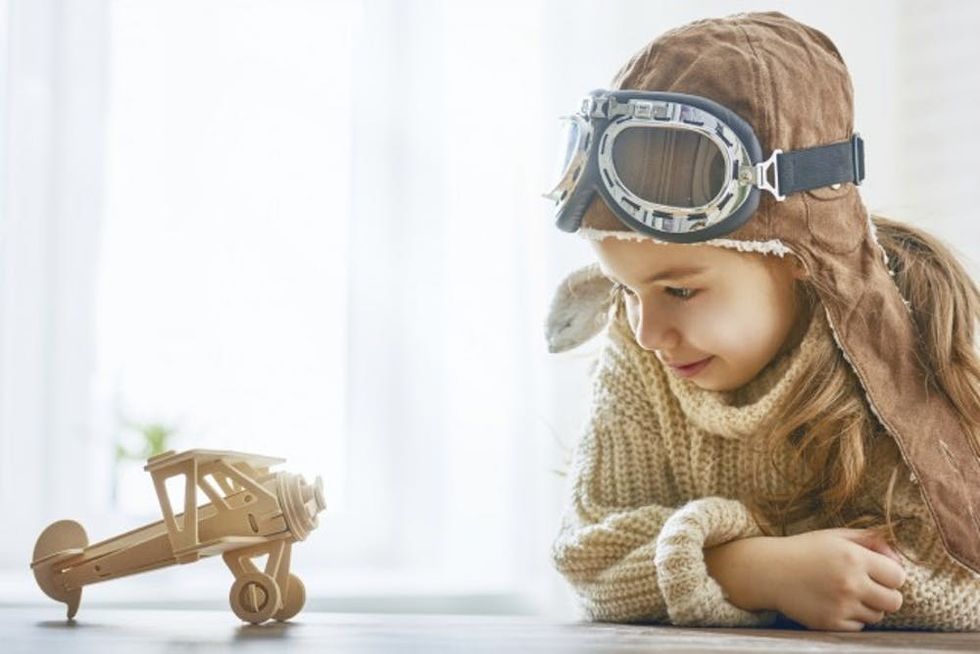 happy child girl playing with toy airplane. the dream of becoming a pilot