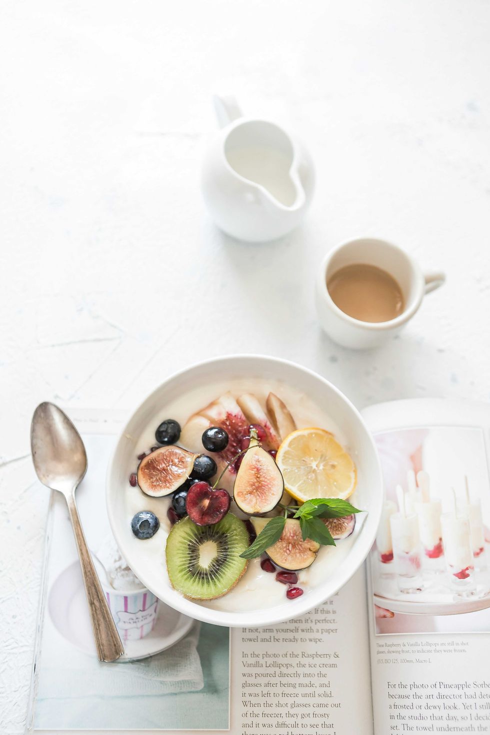 Healthy fruit bowl with kiwi, figs, berries, and coffee on a magazine.