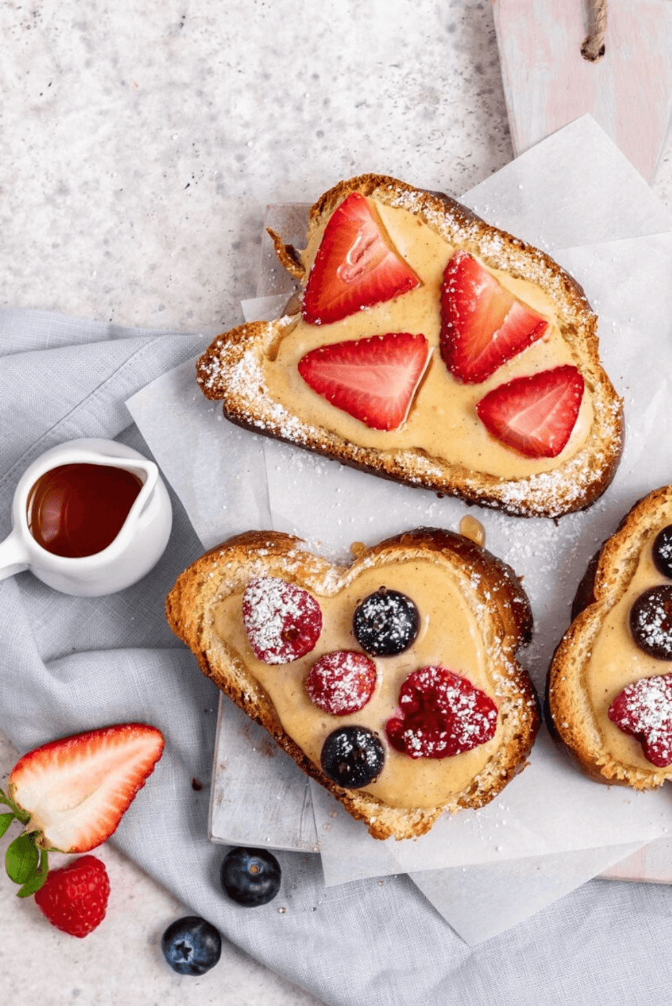 Heart-shaped toast with peanut butter, strawberries, raspberries, and blueberries.