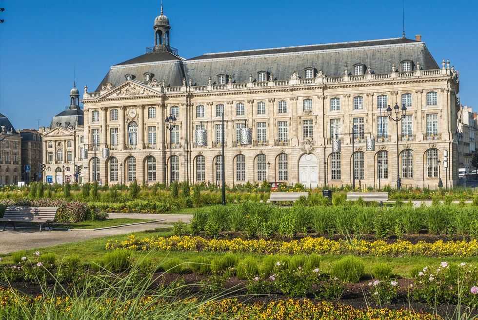 Historic building with ornate architecture and landscaped gardens in the foreground.