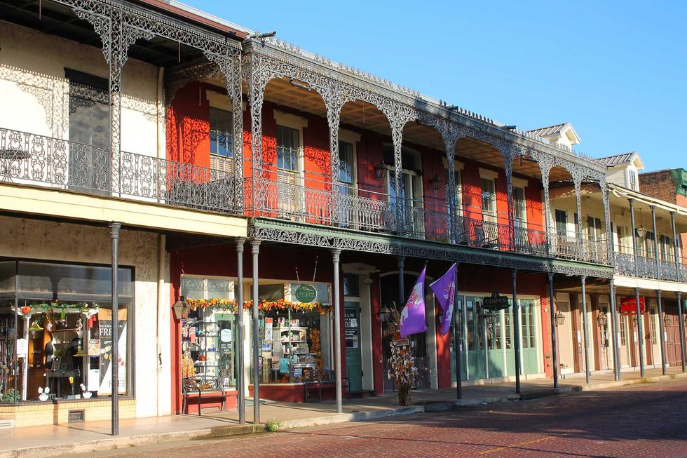 Historic building with ornate balconies and shops below on a sunny day.