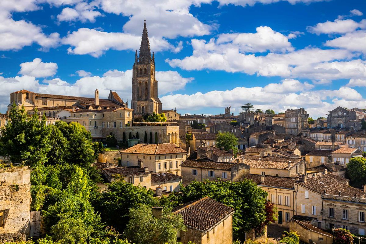 Historic townscape with church tower, rustic buildings, and vibrant blue sky.