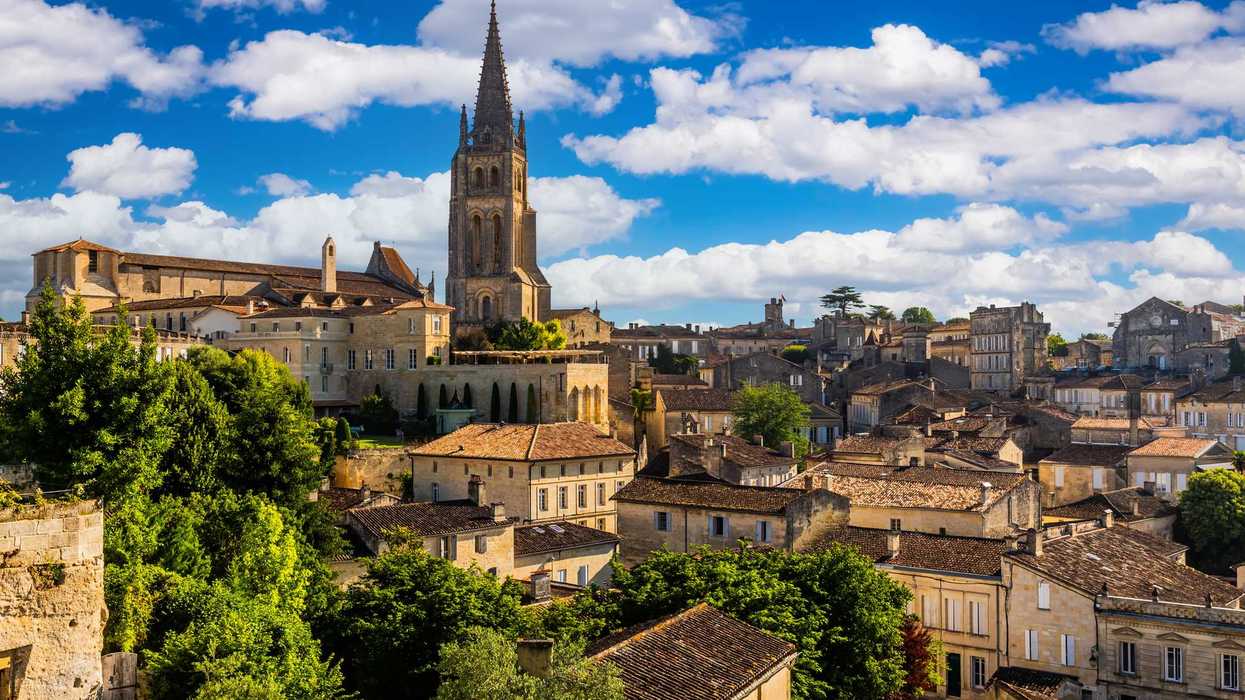 Historic townscape with church tower, rustic buildings, and vibrant blue sky.