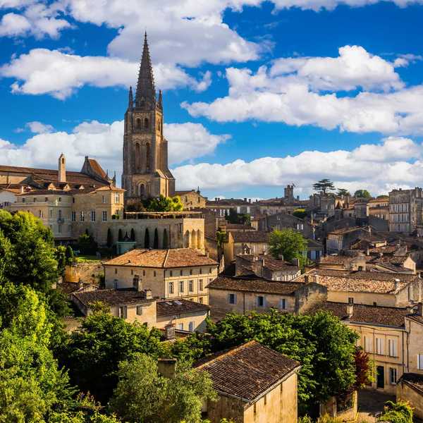 Historic townscape with church tower, rustic buildings, and vibrant blue sky.