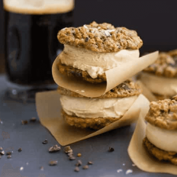 Ice cream sandwiches with oatmeal cookies and a glass of dark beer.