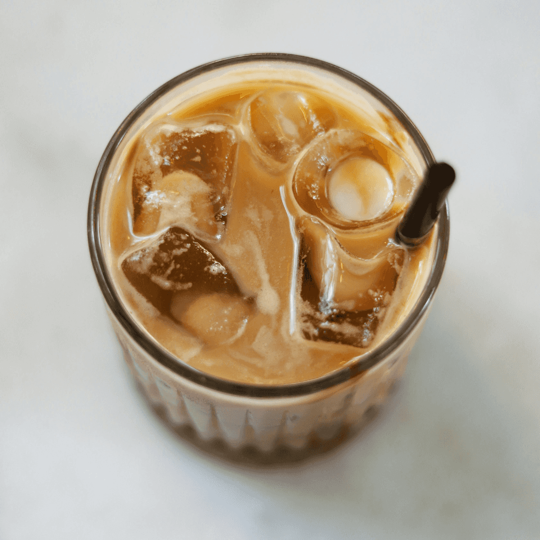 Iced coffee with milk and ice cubes in a glass, viewed from above.