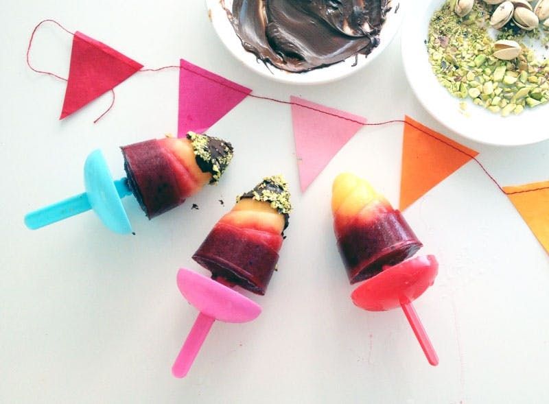3 multi-colored popsicles dipped in chocolate and pistachios  