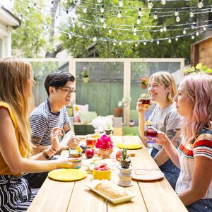 friends sitting around a table for outdoor dining with rainbow decor