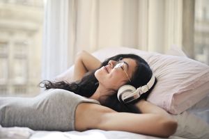A woman is lying down and listening to music. 